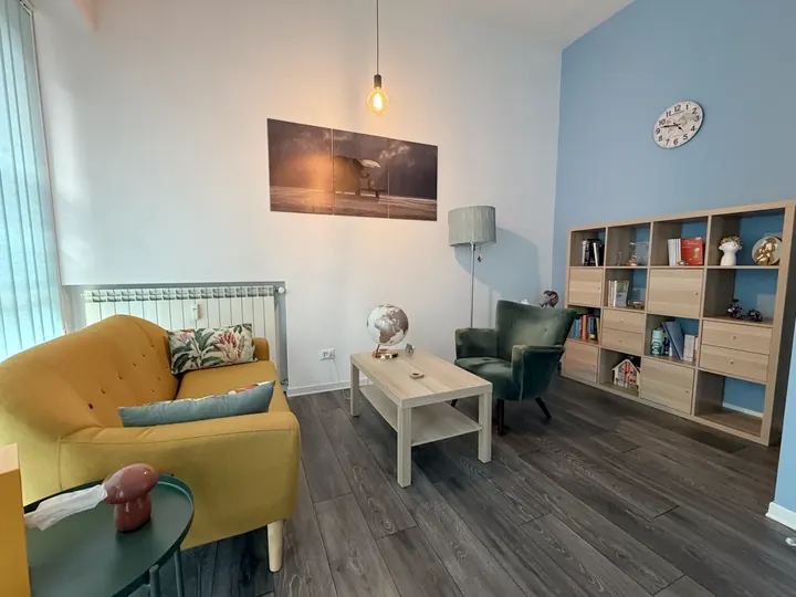 Stanza dei colloqui con divano giallo, poltrona verde e luce calda nello studio a Roma Eur